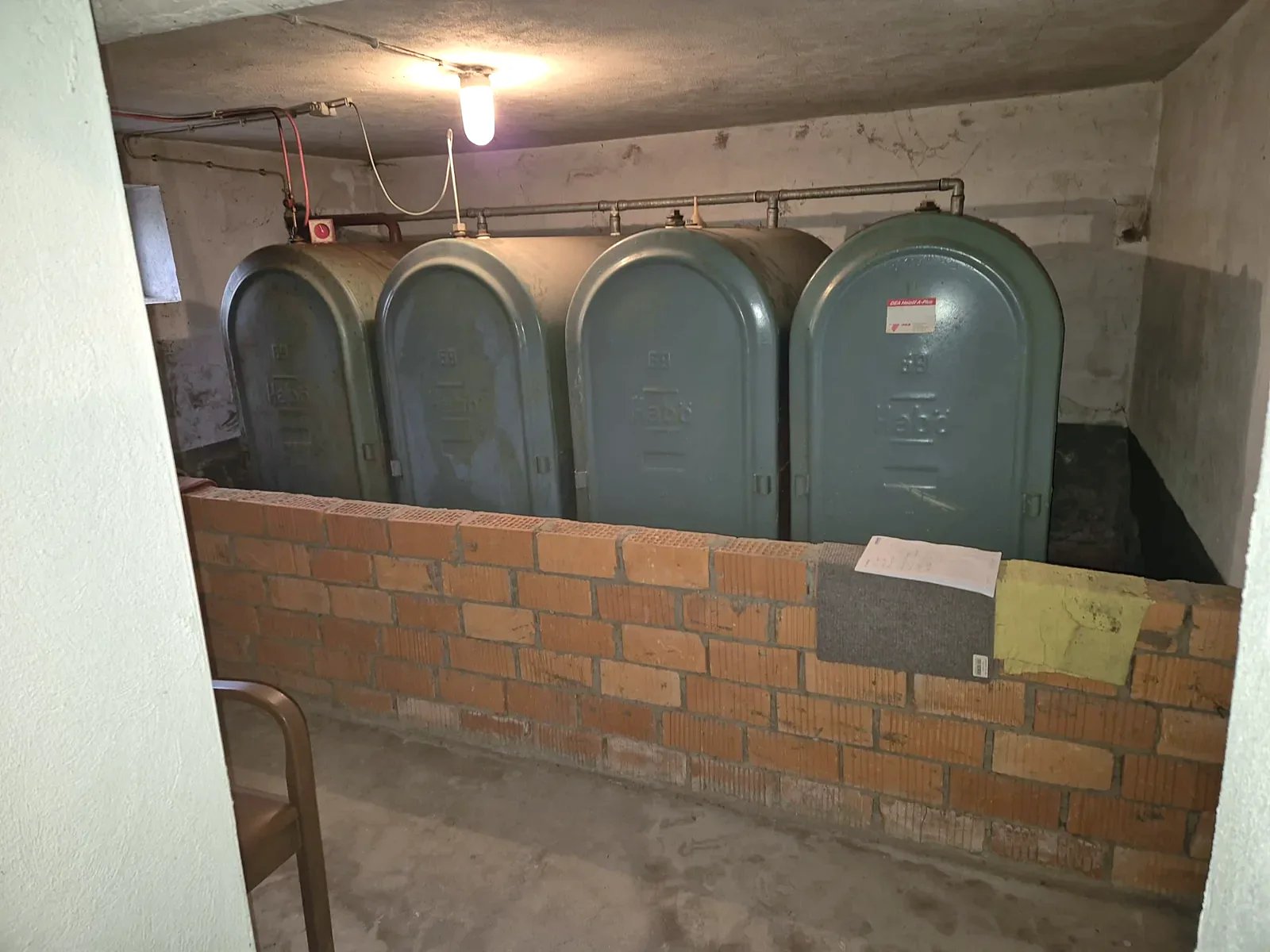 Mehrere Stahltanks hinter einer gemauerten Rückhaltung in einem Kellerraum – Originalfoto